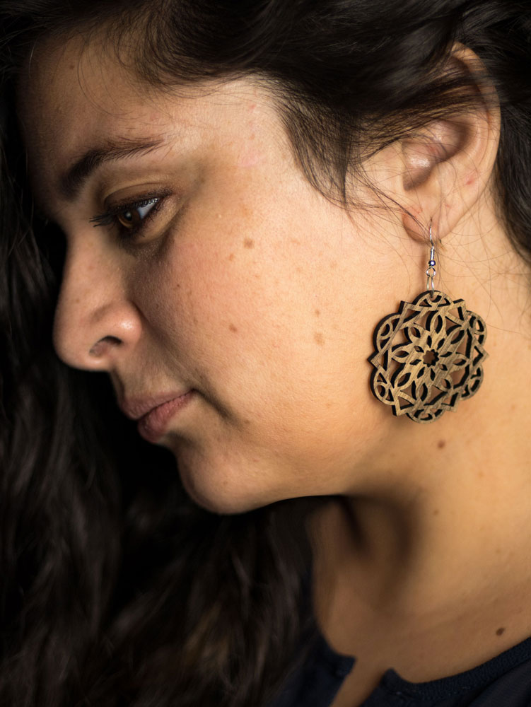 Boucle d'oreille bois DHLaser Design en Noyer motif Canopus floral, portee en gros plan sur oreille, veinage profond, style boheme