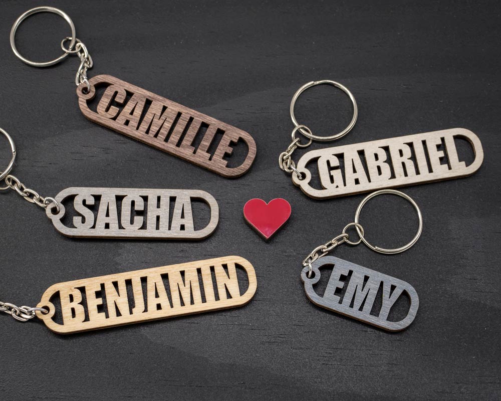 Cinq porte-clés personnalisés en bouleau DHLaser Design prénoms découpés CAMILLE, SACHA, BENJAMIN, GABRIEL et EMY en cinq teintes différentes
