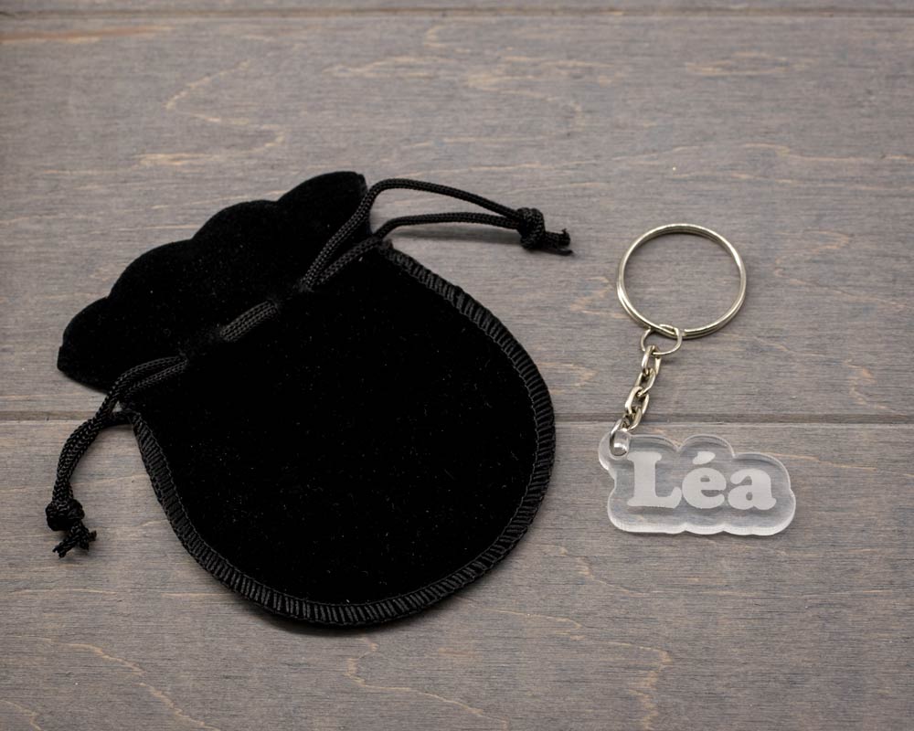 Porte-clé transparent personnalisable forme arrondie avec prénom Léa découpé, présenté avec étui velours noir par DHLaser Design