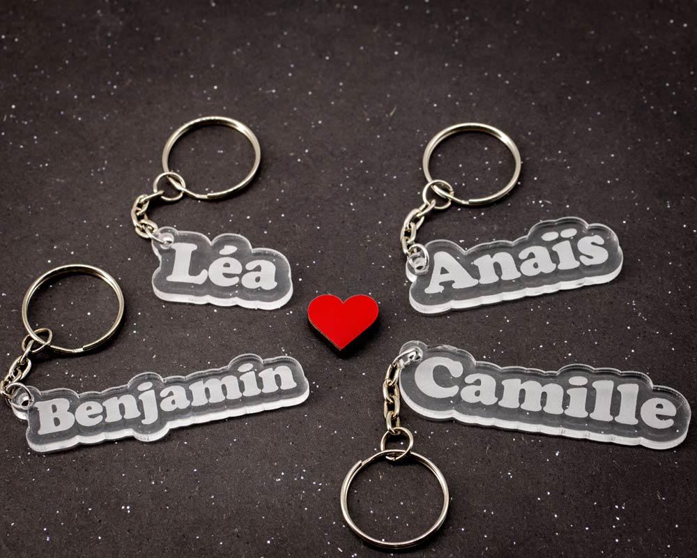 Lot de quatre porte-clés transparents personnalisables avec prénoms Léa Anaïs Benjamin et Camille découpés par DHLaser Design sur fond sombre